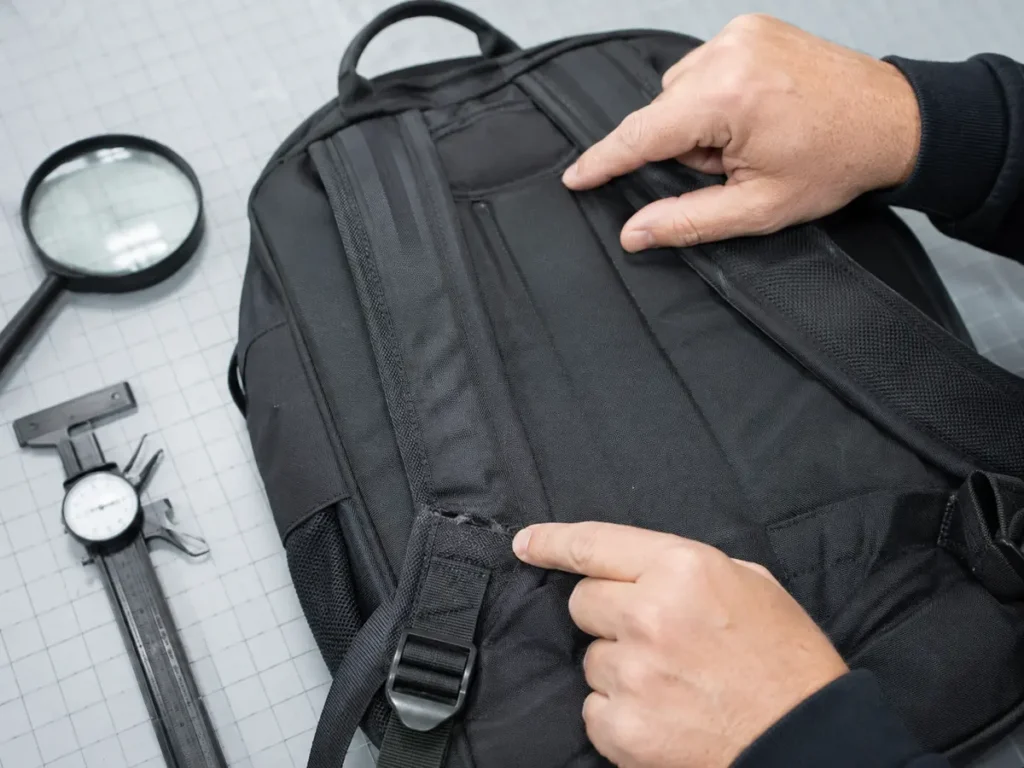 Technician checking common backpack strap failure points