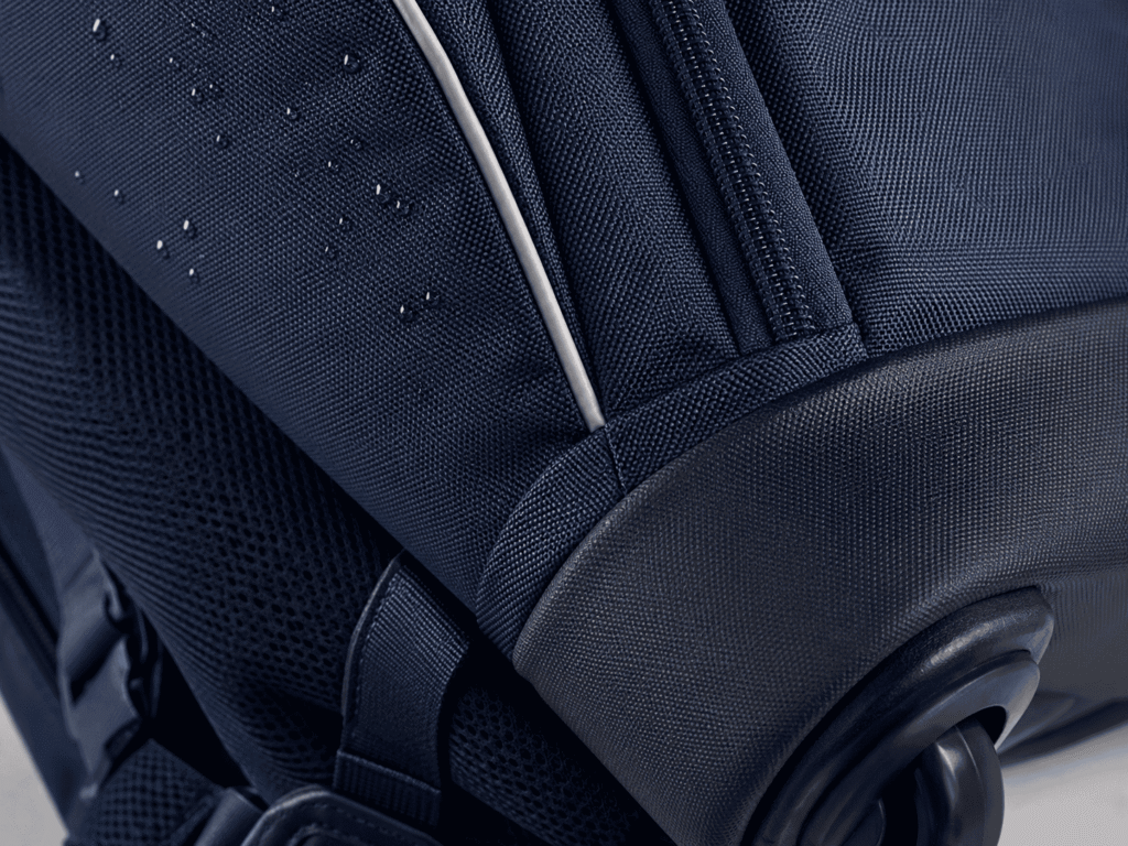 Close-up of woven fabric, reinforced base, zipper and reflective trim on a rolling backpack